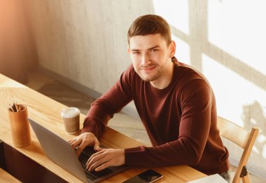 Modern ofisteki çalışma masasında dizüstü bilgisayarda internet taraması yapan neşeli eleman. Yüksek Açı