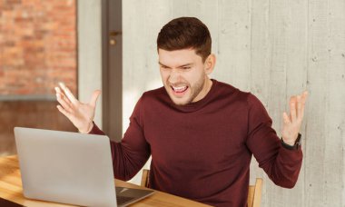 Kızgın ofis çalışanı laptopun başında otururken bağırıyor iş yerindeki bilgisayarla ilgili bir sorun yaşıyor. Seçici Odaklanma