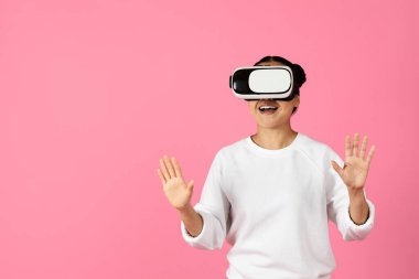 Bir kadın sanal gerçeklik deneyimine dalmış, kulaklık takmış ve elleriyle hareket ediyor. Dijital bir çevreyi keşfederken ifadesi heyecan ve bağlılık taşıyor..