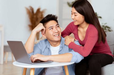 Birlikte vakit geçirmek. Mutlu Asyalı aile oturma odasında dizüstü bilgisayar kullanıyor, hafta sonları dinleniyor, boş yer var.