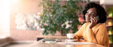 Siyahi genç girişimci telefonda konuşuyor, kafede kahve içiyor, fotokopi çekiyor.