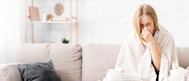 Genç kız hastalandı, battaniyeye sarılı bir şekilde kanepede oturup burnunu sildi.