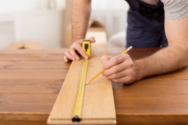 Marangozluk Kariyeri Konsepti. Tanımlanamayan marangoz, atölyesinde çalışan mobilyalardan bir parça yapan ahşap tahtayı ölçüyor. Kırpılmış Vuruş, Seçici Odaklanma