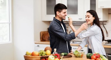 İlişki kavramı. Evlerinde romantik yemekler pişirirken birbirini besleyen mutlu bir aile.
