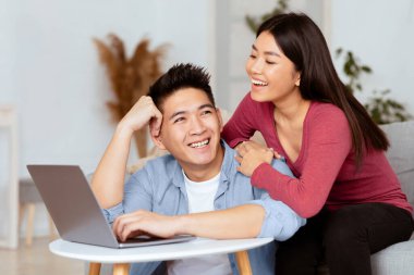 İnternette sörf yapmak. Sevgili Asyalı karı koca dizüstü bilgisayarla rahatlıyor, internette video seyrediyor,