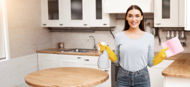 Temizlik Hizmetleri Konsepti. Mutfakta elinde mikrofiber bez ve sprey deterjan tutan gülümseyen kız.
