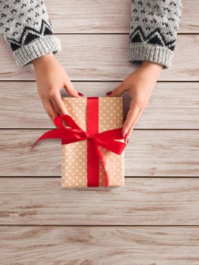 Kadının ellerini kaydırılan Noel ya da diğer tatil el yapımı mevcut kırmızı kurdele ile kağıt ver. Kutusu, dekorasyon hediye ahşap tablo kopya alanı, üstten görünüm