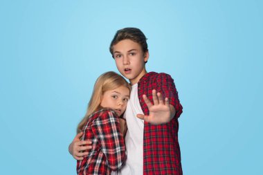 Aile içi şiddet kurbanları. Ağabeyi küçük kız kardeşini kucaklıyor, onu aile içi şiddetten koruyor, mavi arka planı ve boş alanı var.