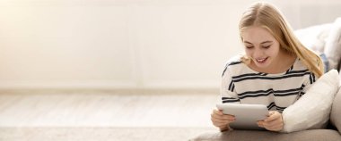 Young Girl Watching Media Content on Tablet, Laying on Sofa at Home, Copy Space
