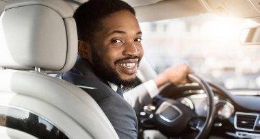 Yeni araba. Sürücü koltuğunda oturan neşeli siyah adam, satın aldıktan sonra yeni otomobil kullanıyor. Panorama, Seçici Odaklanma