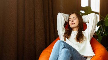 İş kavramından uzaklaşmak. Kapalı gözlü serbest çalışan kız koltukta dinleniyor.