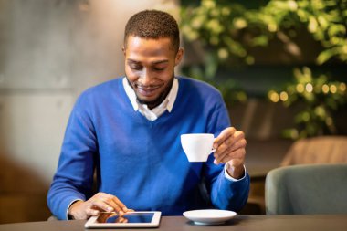 Teknoloji Konsepti. Modern kafede oturan, kahve içen ve tablet kullanan mutlu siyahi öğrencilerin ön görüntüsü.