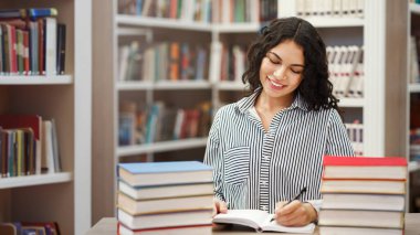 Genç Bayan Öğretici. Not defterinde yazan mutlu İspanyol profesör, üniversite kütüphanesinde masa başında oturuyor.