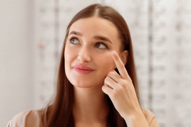 Lenslerin nasıl uygulanacağı konsepti. Göz merceği takan, yana bakan genç bir kadının yakın portresi.