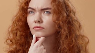 Çarpıcı kıvırcık kızıl saçlı bir kadın çenesini elinde dinlendirirken düşünür. Yüzündeki ifade, derin bir düşünceye ya da şüpheciliğe işaret ediyor..