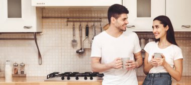 Birlikte vakit geçirmek. Modern mutfakta kahve içen genç ve güzel bir adam ve kadının tam boy portresi.