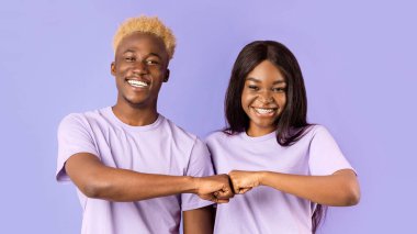 Yakışıklı siyah adam ve hoş bayan menekşe arka planda yumruk tokuşturuyorlar.