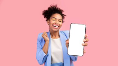 Boş ekranlı cep telefonu tutan mutlu siyah kadın Pastel Pembe duvarın üzerinde izole edilmiş, kazanan jest. Model