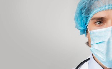 Coronavirus 'un Korumasında. Medikal Maskeli ve Saç Ağı Takan Güvenilir Erkek Doktor 'un Yarım Yüzlü Portresi Kamera, Panorama ve Boş Alan Bakıyor