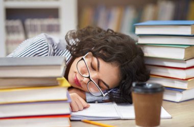 Kütüphanede uyumak. Yorgun Meksikalı kız öğrenci kitapların üzerinde kestiriyor, sınavlara hazırlanırken yoruluyor.