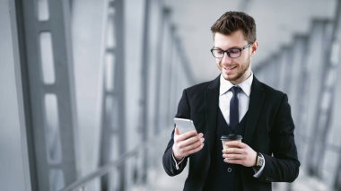 Haberleri okuyorum. Gülümseyen sakallı adamın portresi, takım elbiseli ve elinde cep telefonu olan gözlüklü kahve fincanı.