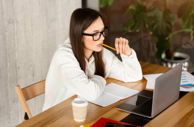 Gözlüklü kız işi analiz ediyor, ağzında kalem tutuyor, boş yer var.