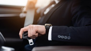 Güvenli Kal Kavramı. Takım elbiseli, kol saati takan, otomatik emniyet kemeri takan, tanınmayan bir adamın yakın plan görüntüsü.
