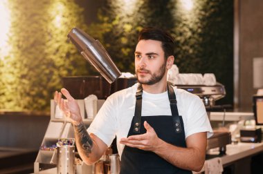 Profesyonel barmen barmen Shaker kullanıyor. Kahve yapıyor. Kafeteryadaki barın önünde duruyor..