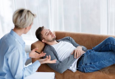 Depresyonla savaşmak. Ofiste koltukta uzanmış psikologla konuşan erkek hasta. Seçici Odaklanma