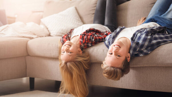 Funny Brother And Sister Kids Sitting On Couch Upside Down Having Fun At Home. Selective Focus