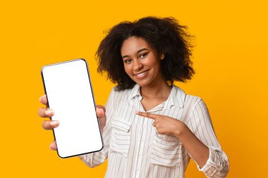 Uygulamayı kontrol et. Siyah bir kadının elinde siyah bir ekranla dijital tableti göstermesi, sarı arka planda poz vermesi, boş bir alan bırakması.