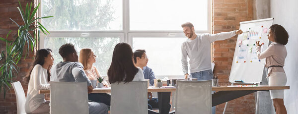 Side view of caucasian man and black woman making presentation for international business team in office