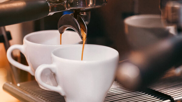 Крупный план работы кофе-машины с чашками, бариста делает кофе эспрессо в кофейне. Селективный фокус, обрезка
