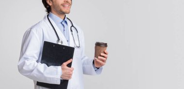 Kliniğe gir. Tanımlanamayan erkek doktor elinde tıbbi çizelge tutuyor ve paket kahve içiyor. Kesilmiş resim, fotokopi alanı olan panorama.