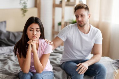 Kavgadan sonra uzlaşma. Karantina süresince evde yatakta oturan ve eşine dokunan bir kadın.