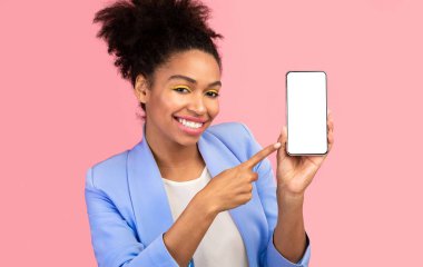 Yeni bir şey dene. Cep telefonunu işaret eden mutlu afro kız reklam için siyah ekranlı, pembe duvarlı.