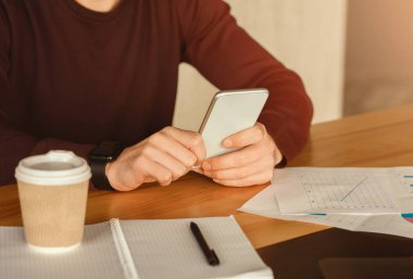 Business App. Unrecognizable Guy Using Smartphone Sitting At Workplace In Modern Office. Cropped, Selective Focus