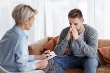 Depresyon danışmanlığı. Ofiste randevu sırasında profesyonel psikolog not alırken umutsuz bir adam mutsuz bir hayatı anlatıyor. Seçici Odaklanma