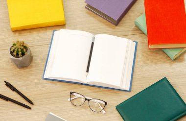 Ders çalışma zamanı. Eğitim kitaplarının ahşap masanın üzerindeki düzeninin üstünde, kalem ve düz bir defter var.