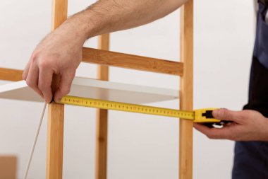 Marangozluk Mesleği. Marangoz, içeride çalışan bantlı mobilyalarla ahşap rafı ölçüyordu. Zanaatkar Kabineyi Yapıyor. Yakın çekim.