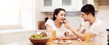 Evde Kahvaltı Yapıyorum. Mutlu erkek arkadaş, güzel kızına mutfakta ev yapımı bisküvi veriyor.