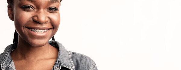 Dental Braces. Portrait Of African Lady With Brackets On Teeth Smiling To Camera Posing In Studio On White Background.