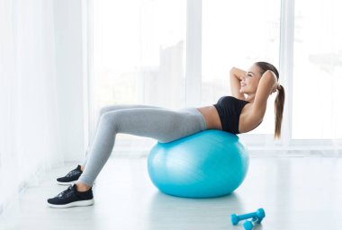Spor salonunda fitness topu ile çalışma dışarı, beyaz oda, kopya alanı basında kas egzersizleri yapıyor kadın