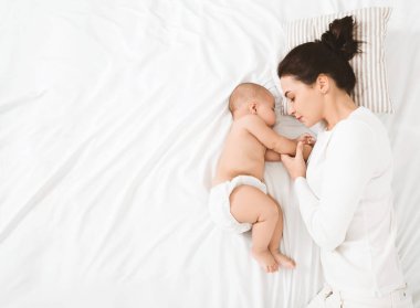 Uyku zamanı. Dokunmadan eller, üstten görünüm, kopya alanı annesiyle yatakta uyuyan bebek