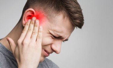 Genç adamın kulağı ağrıyor, otit isi var, iltihaplı kafasına dokunuyor, yakın çekim, boş alan.