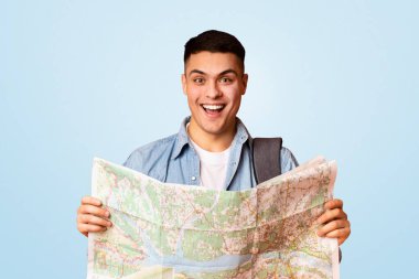 Sırt çantasında şehir haritası, turuncu stüdyo geçmişi, gezi konsepti olan mutlu genç bir gezgin.