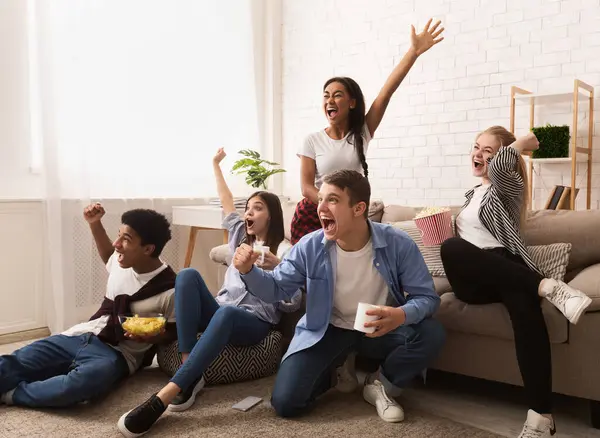 Duygusal futbol hayranları. Gençler evde maç izleyip zaferi kutluyorlar.