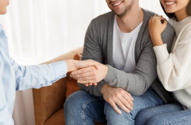 Ofiste etkili bir aile terapisinden sonra tanınmayan bir çift ve psikolog el sıkışması. Seçici odak, kırpılmış