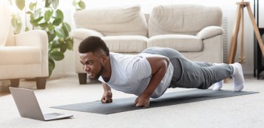 Ev antrenmanı. Spor Genç Siyah Adam Dizüstü bilgisayarın önünde Yumruk Egzersizi Yapıyor, Spor Derslerini Çevrimiçi, Panorama