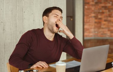 Uykucu ofis elemanı laptopta esniyor, iş yerinde oturuyor. İş yorgunluğu. Seçici Odaklanma